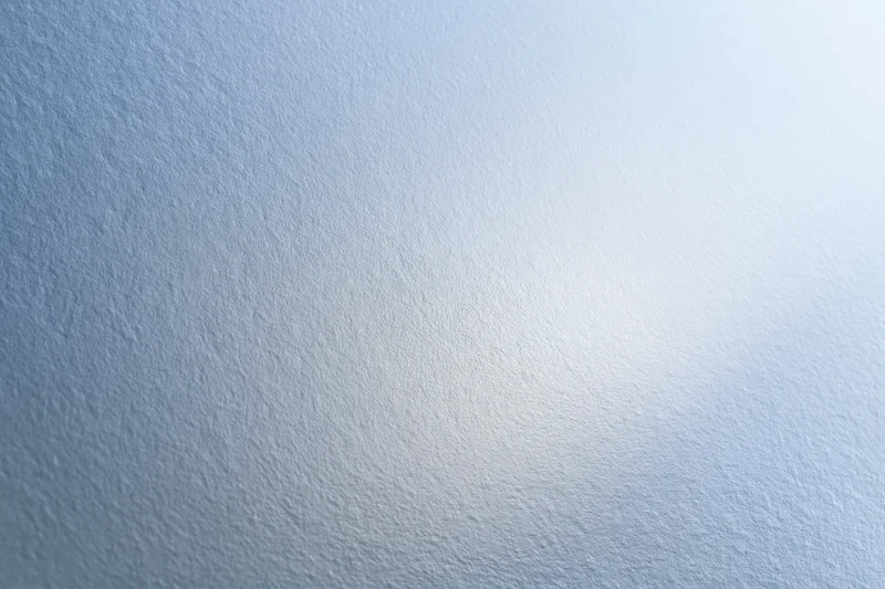 Frosted glass surface filling the frame with soft light gradient and subtle texture