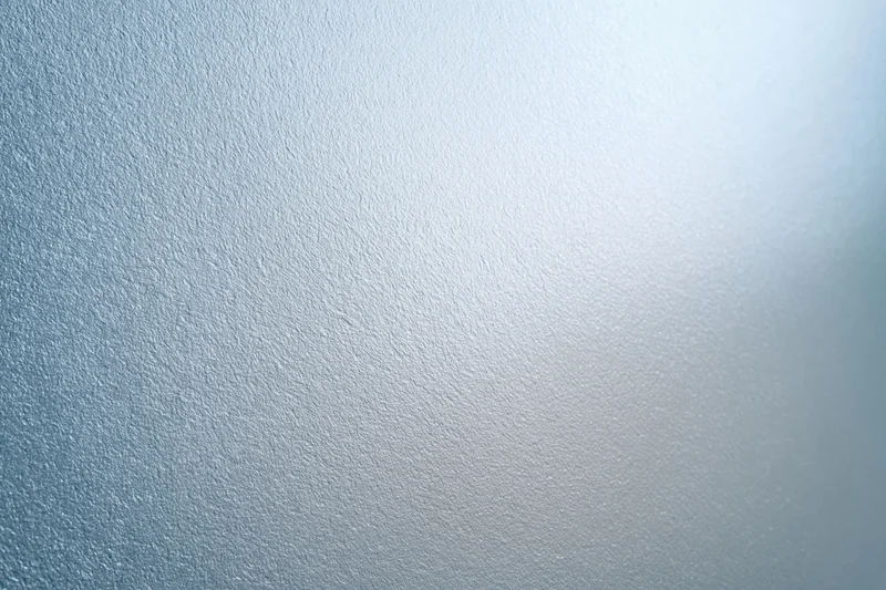 Frosted glass surface filling the frame with a smooth translucent texture and soft light gradient