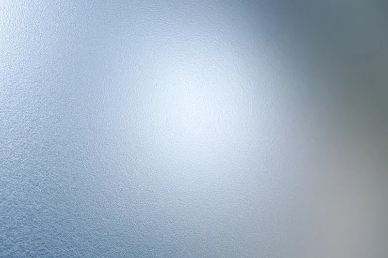Frosted glass surface filling the frame with a smooth translucent texture and soft light gradient