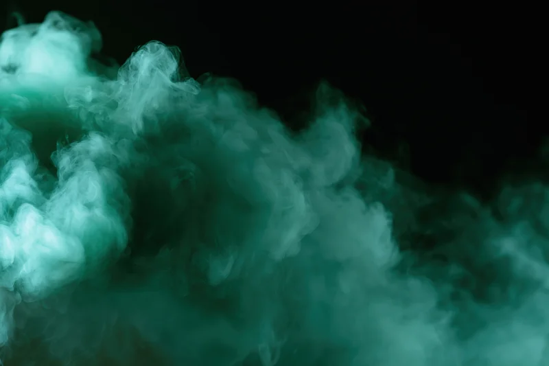 Green-tinted smoke billowing upward against a black background with copyspace