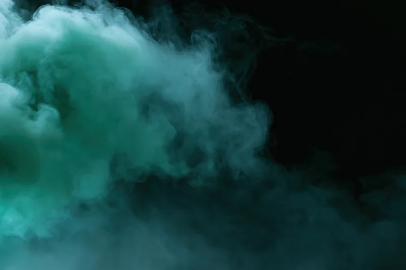 Green-tinted smoke billowing upward against a dark background with copyspace