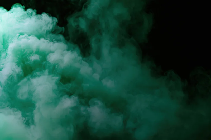 Green-tinted smoke billowing upward against a dark background