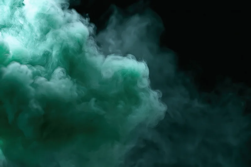 Green-tinted smoke billowing upward against a dark background with copyspace