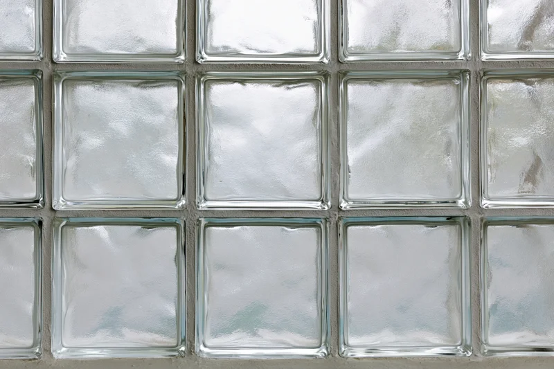Grid of frosted glass blocks arranged in three rows with cement mortar joints on a wall