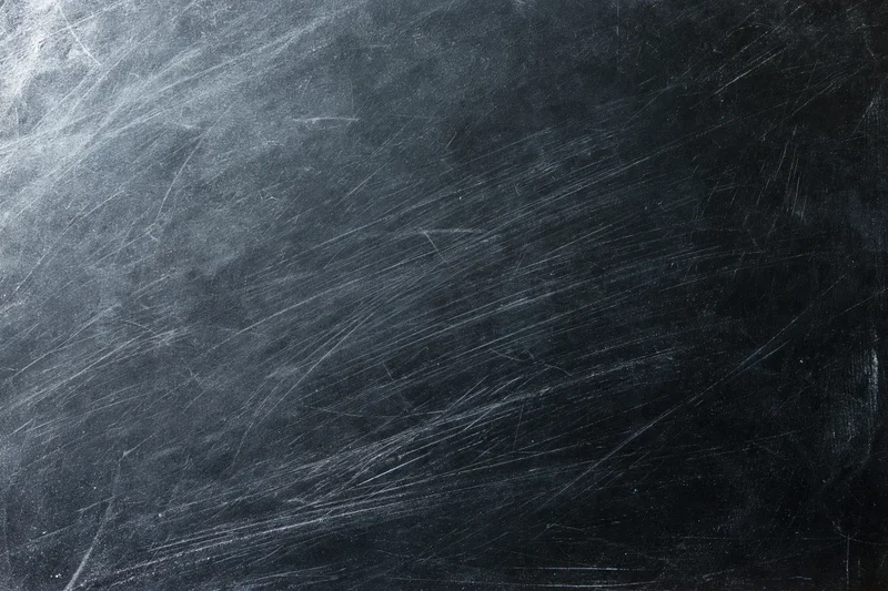 Heavily scratched black surface texture in close-up flat lay arrangement