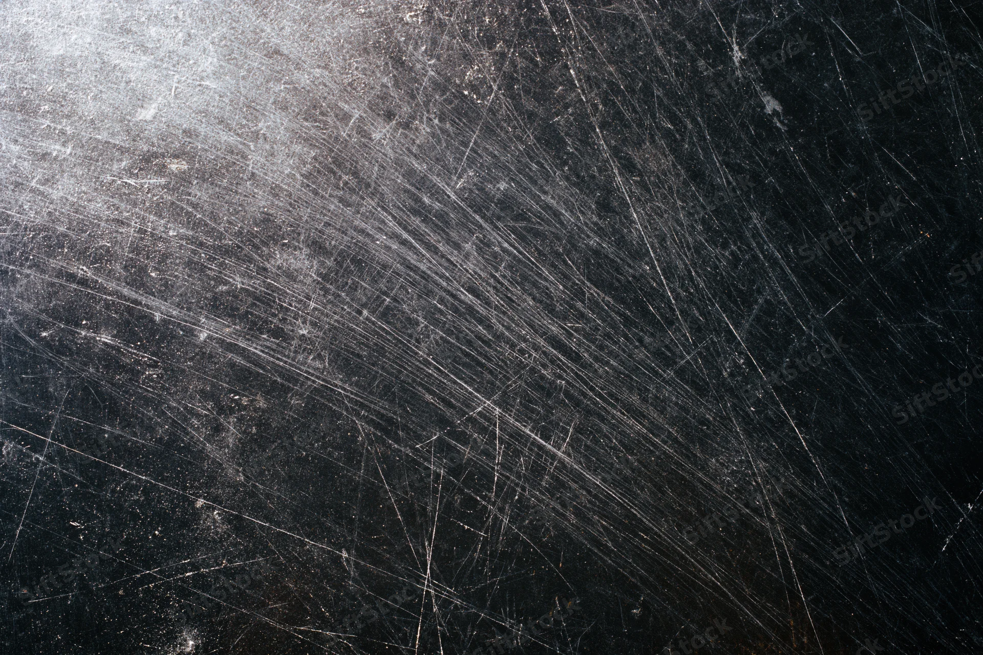 Heavily scratched black metal surface in close-up flat lay view