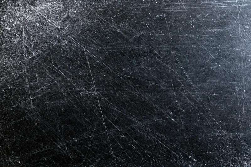 Heavily scratched black surface texture in close-up flat lay arrangement