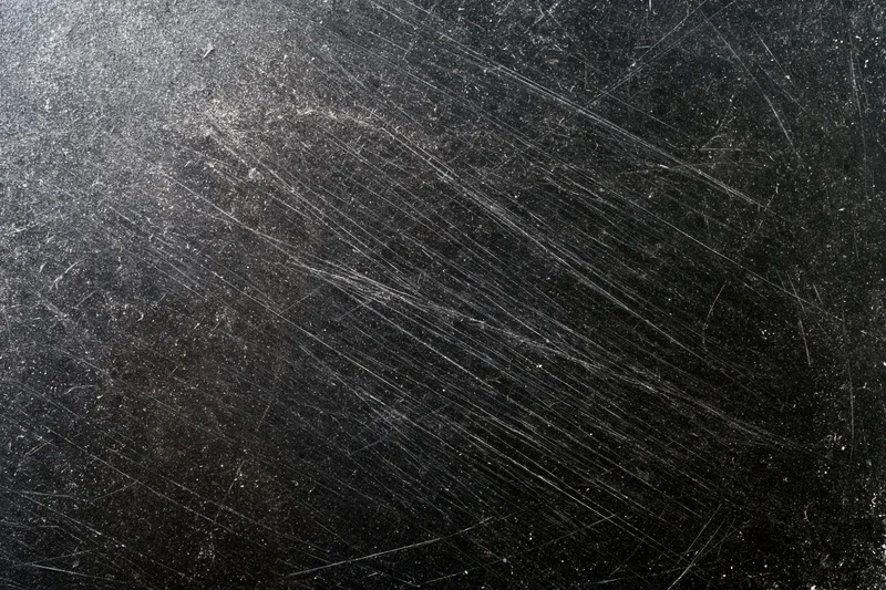 Heavily scratched black surface in close-up flat lay view