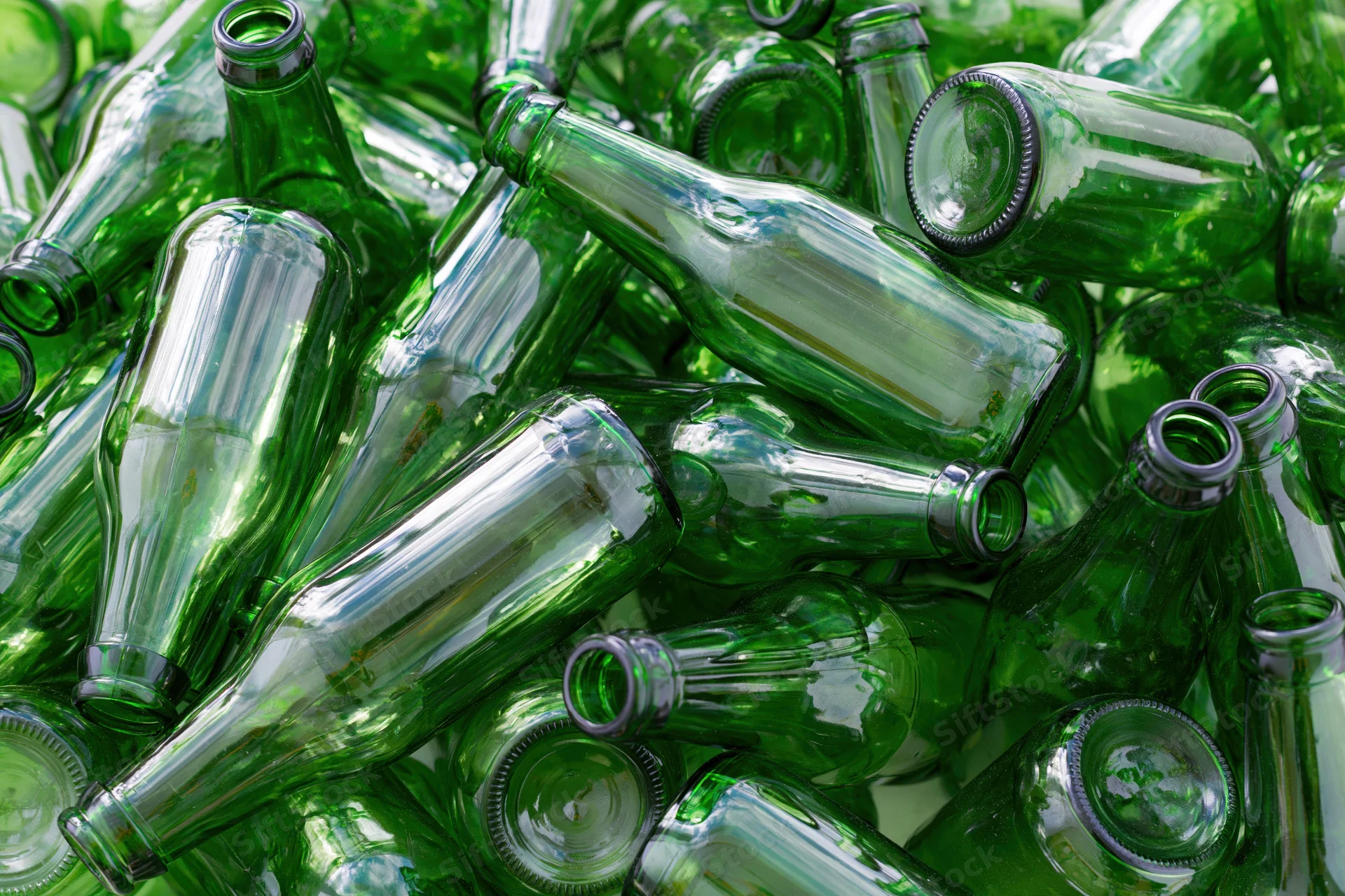 Pile of empty green glass beer bottles scattered in heap