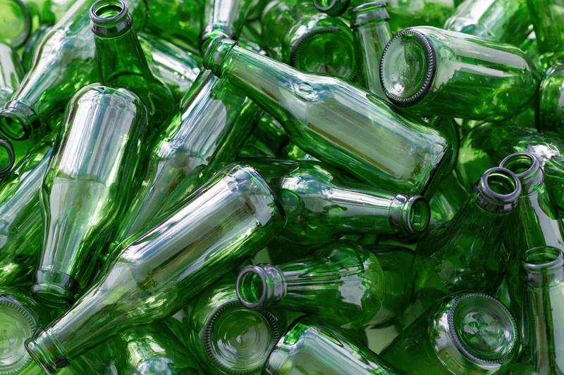Pile of empty green glass beer bottles scattered in heap