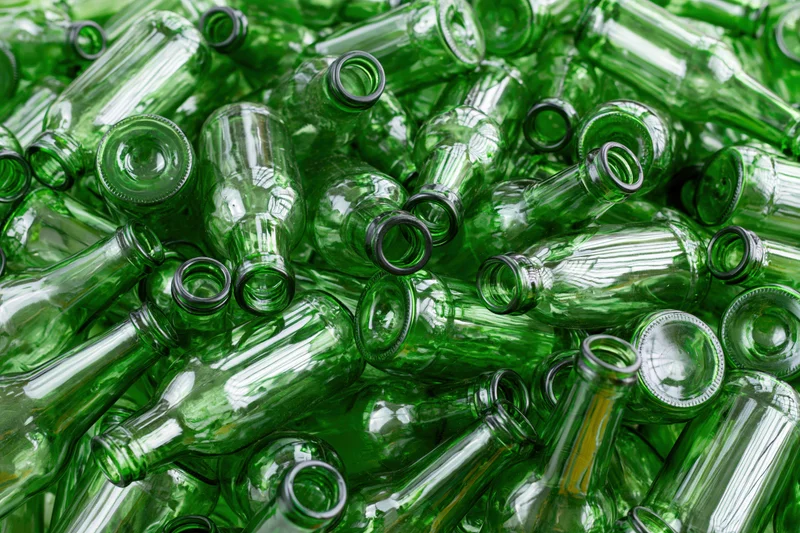 Pile of empty green glass beer bottles scattered in disarray