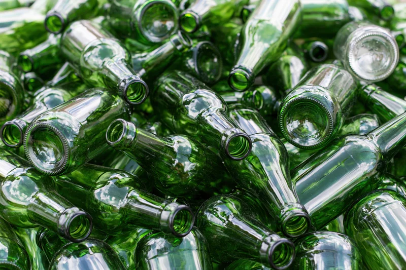 Pile of empty green glass beer bottles scattered and stacked together