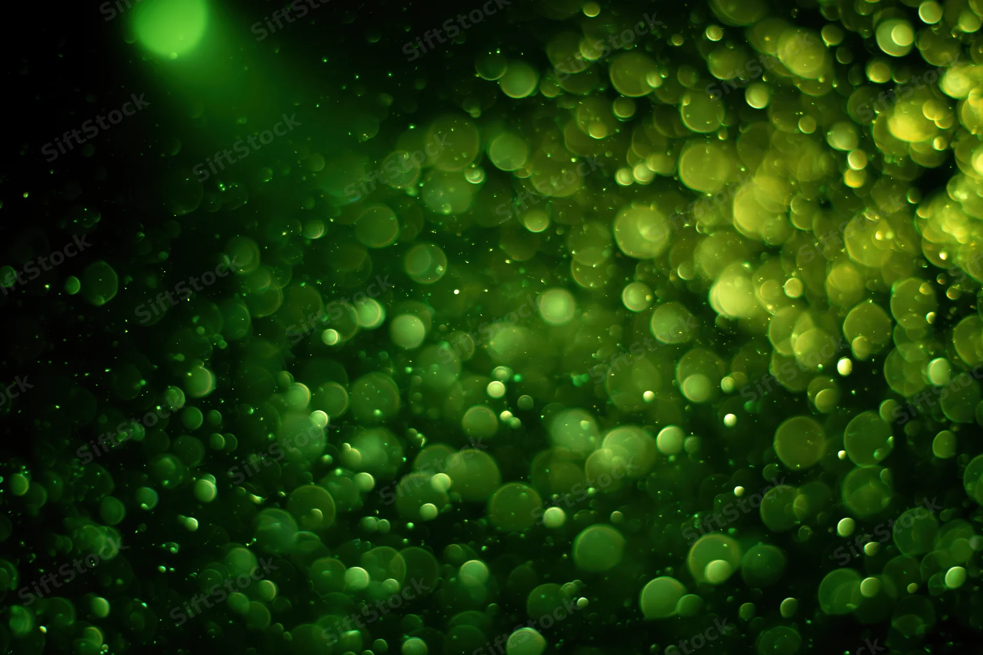 Green light particles suspended in dark air creating a soft glowing bokeh effect