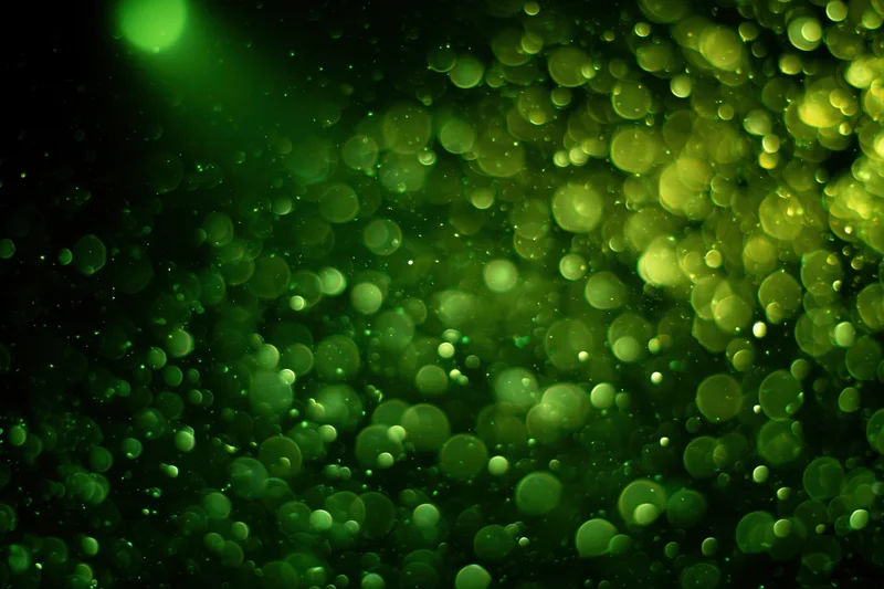 Green light particles suspended in dark air creating a soft glowing bokeh effect