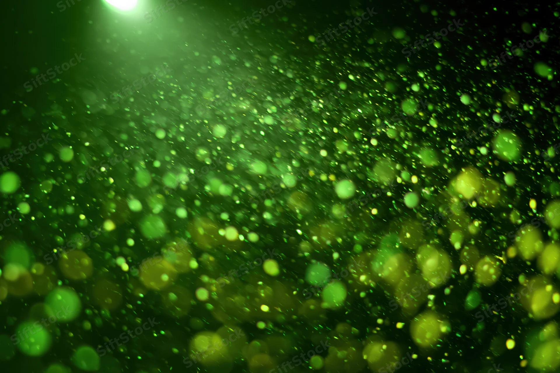Green light particles floating in dark air with soft glow and bokeh effect