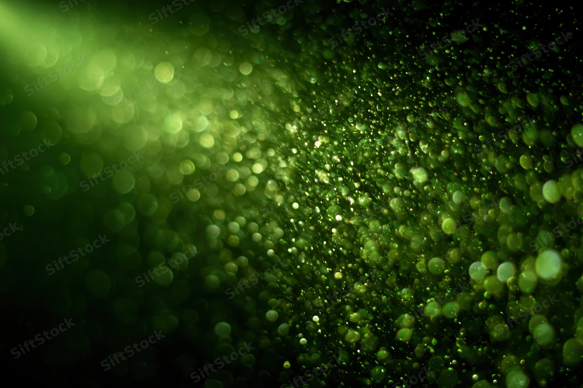 Green light particles suspended in dark air with soft bokeh effect