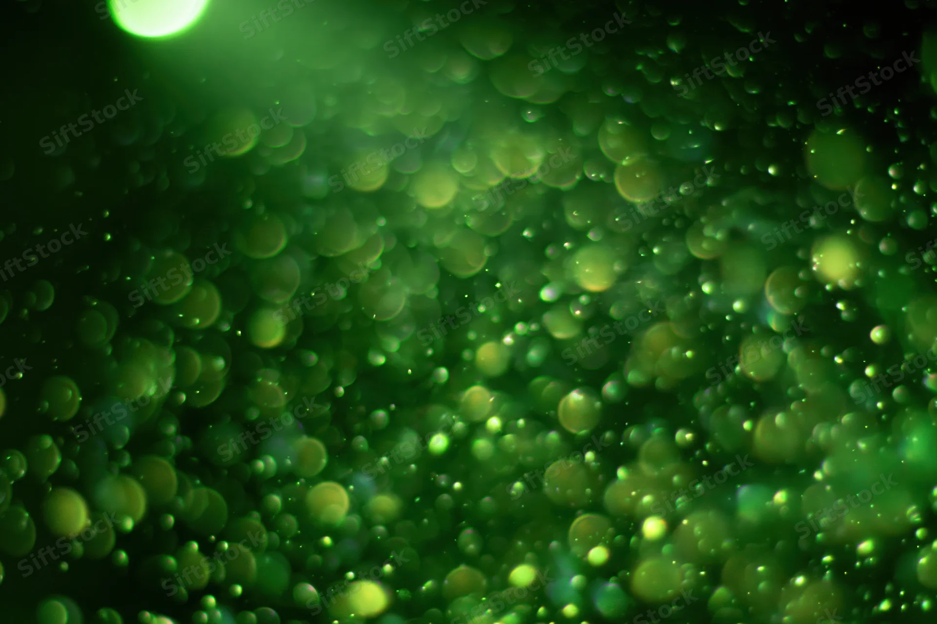 Green light particles suspended in dark air with soft bokeh effect