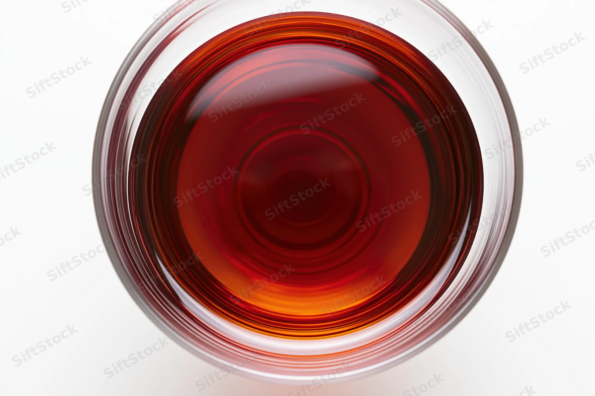 Red wine in a glass viewed from directly above, nearly full, on a white surface