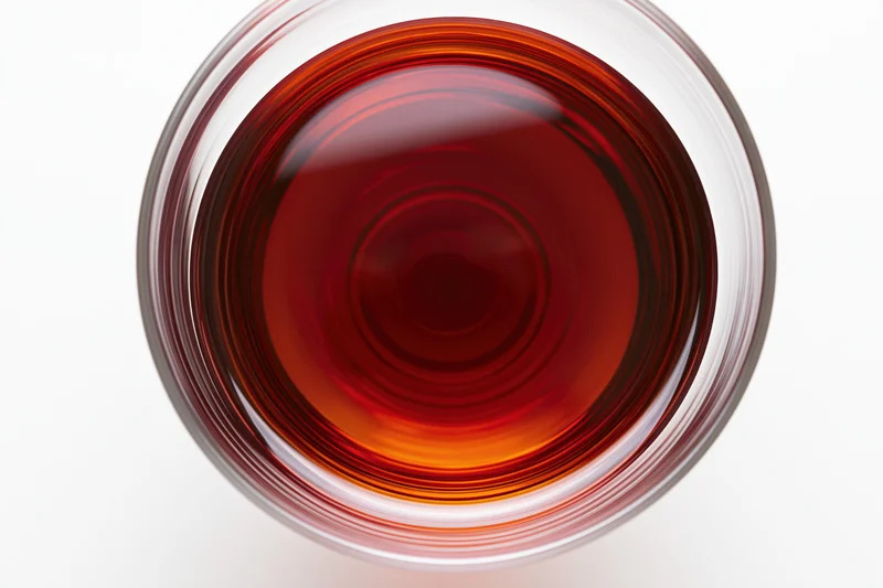 Red wine in a glass viewed from directly above, nearly full, on a white surface