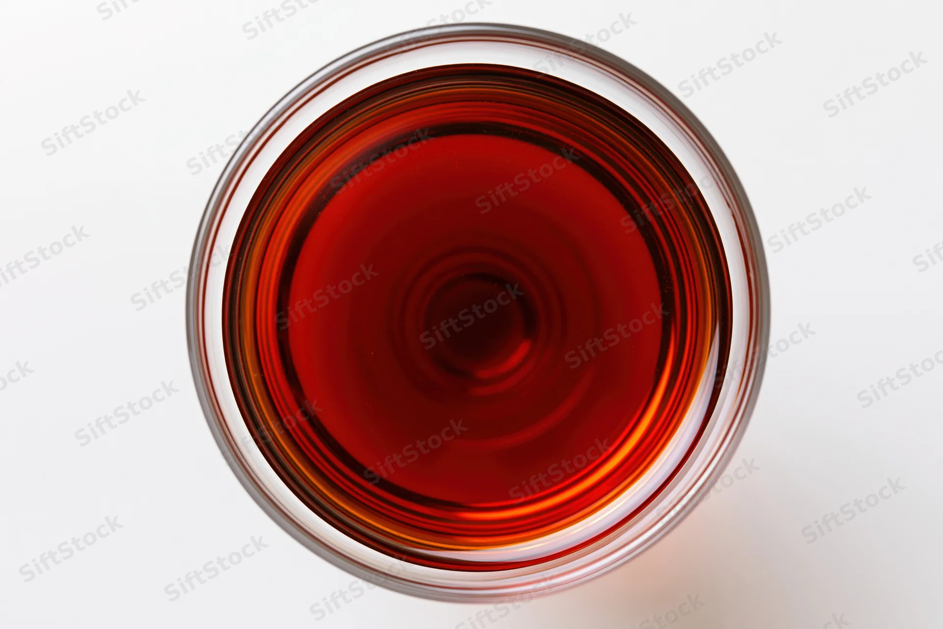 Red wine in a glass viewed from directly above on a white surface
