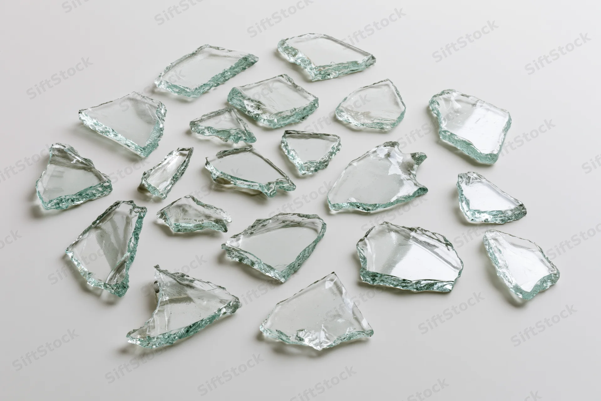 Broken glass shards scattered on a plain white surface