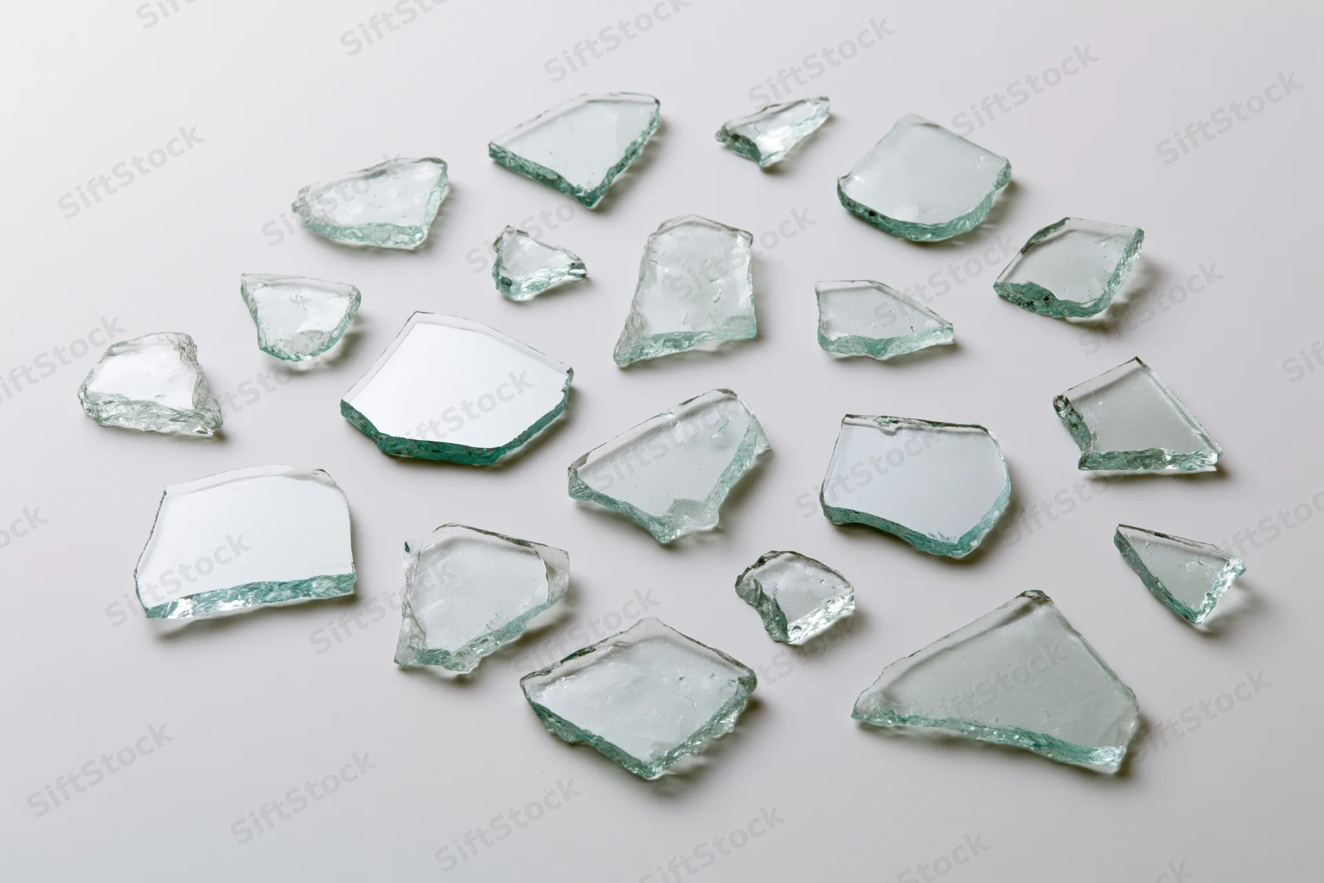 Broken glass shards scattered across a white surface