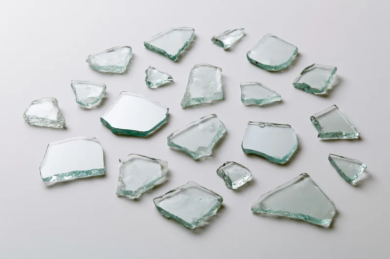 Broken glass shards scattered across a white surface