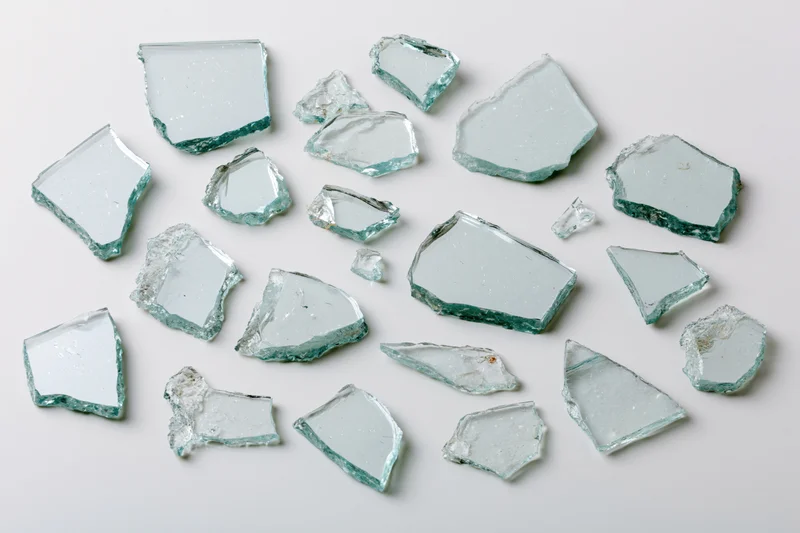 Broken glass shards scattered on a white surface