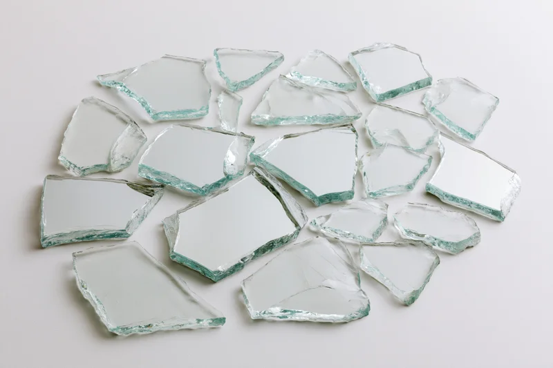 Broken glass shards scattered on a white surface
