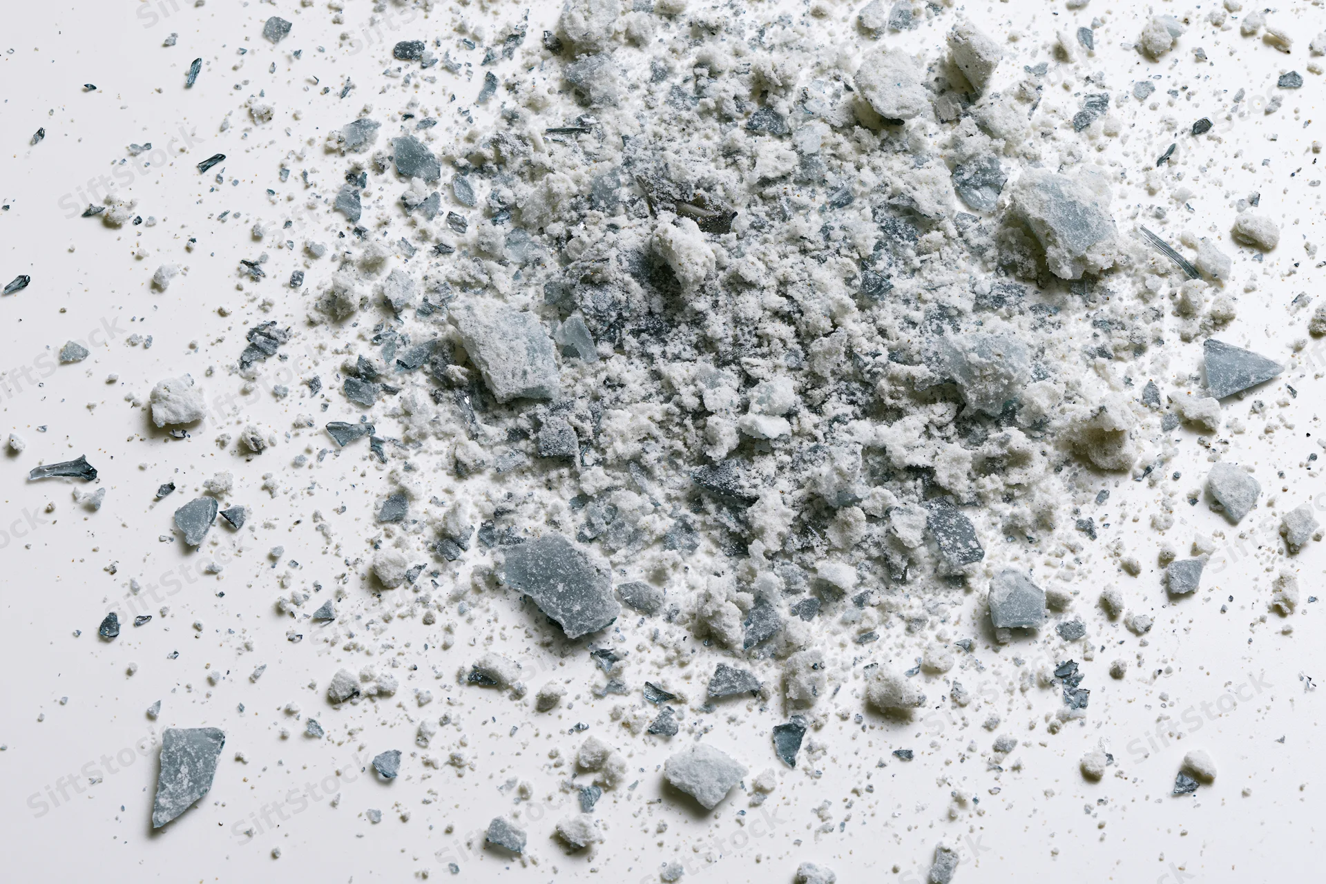Scattered glass shards and fine debris fragments on a white surface