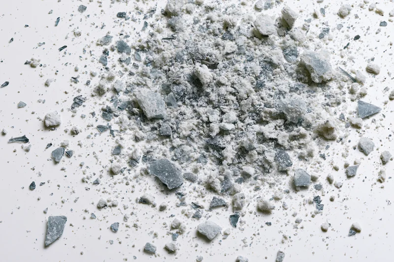 Scattered glass shards and fine debris fragments on a white surface