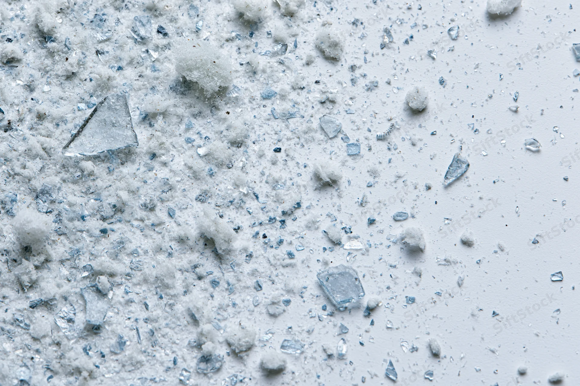 Scattered glass shards and fine debris fragments on a white surface