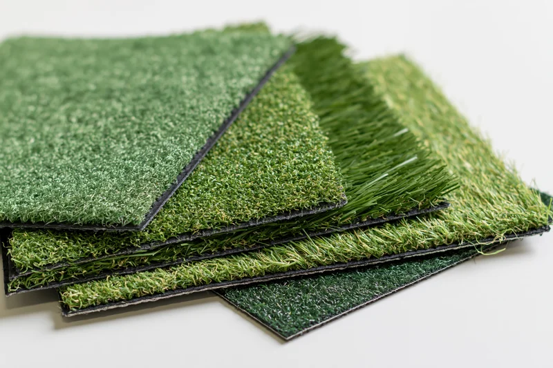 Artificial grass turf samples fanned out in overlapping layers on white background