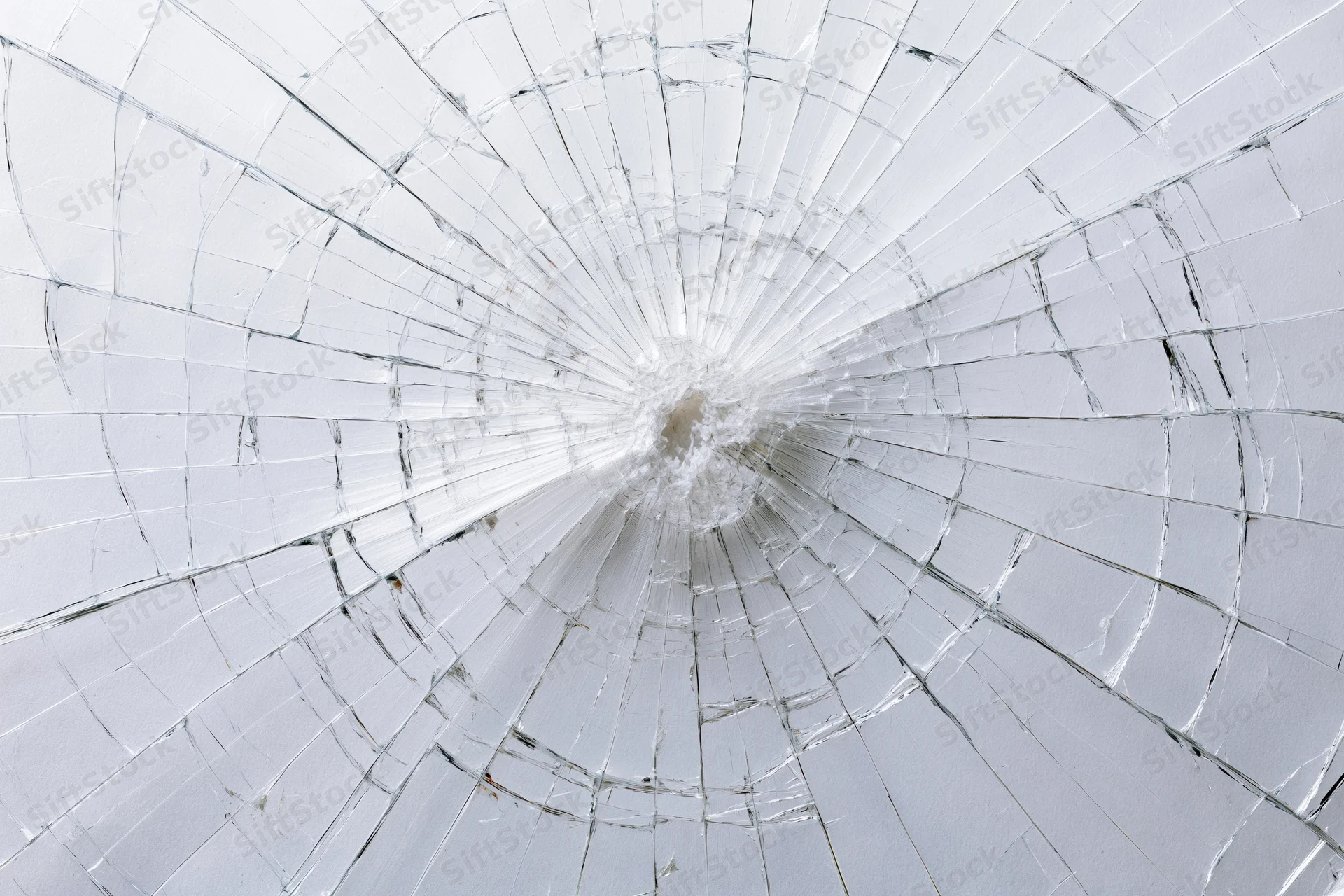 Shattered glass pane with radial cracks emanating from central impact point