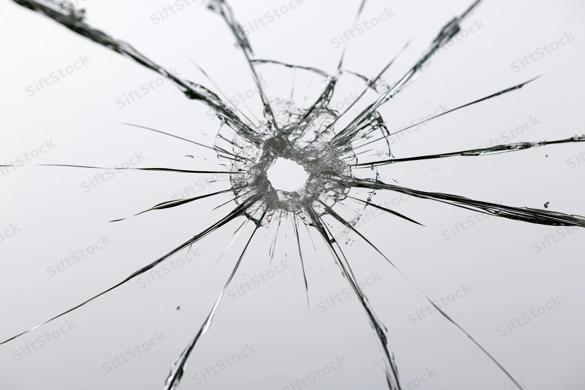 Shattered glass pane with central impact point radiating cracks across transparent surface