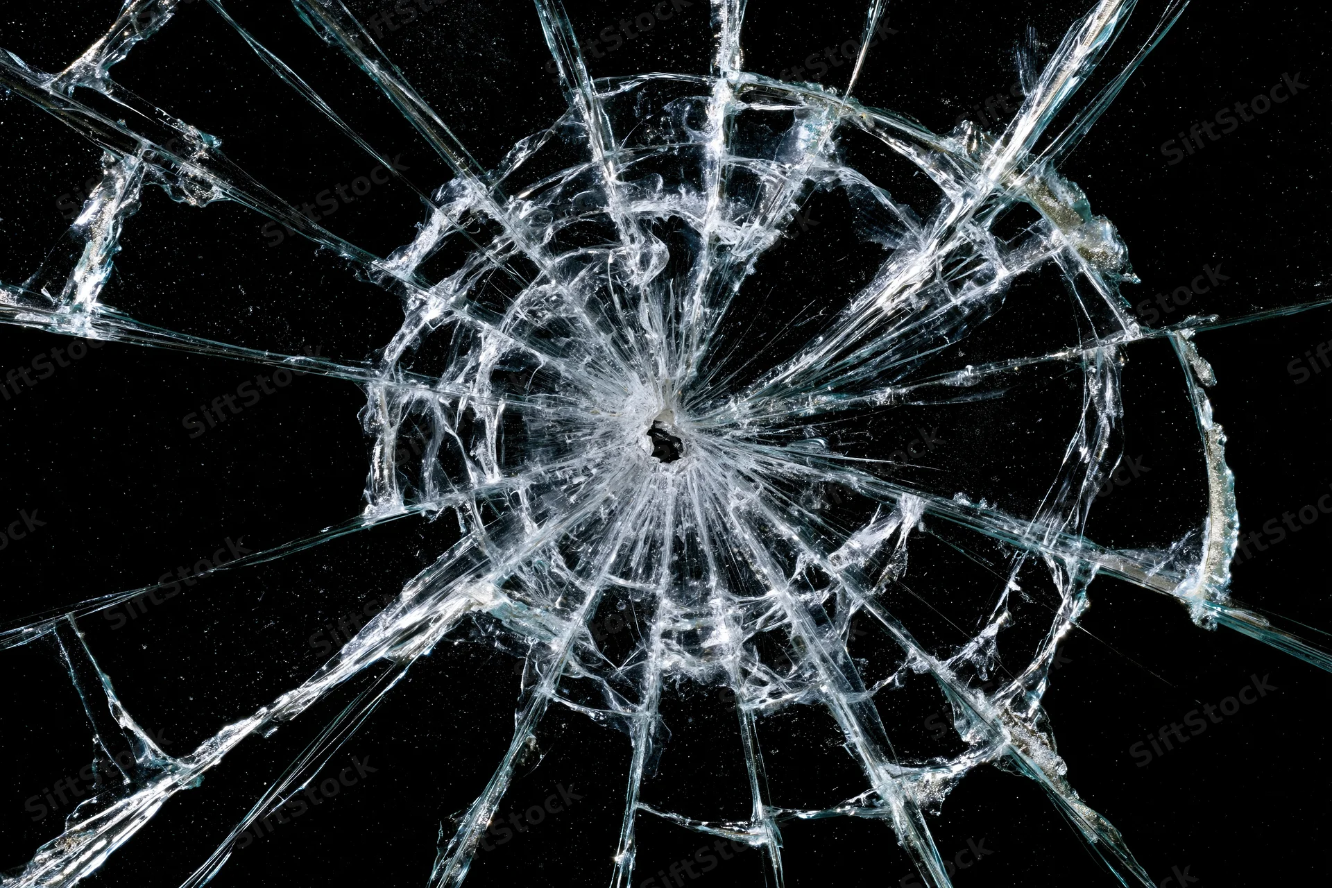 Shattered glass with a central impact point radiating cracks against a black background