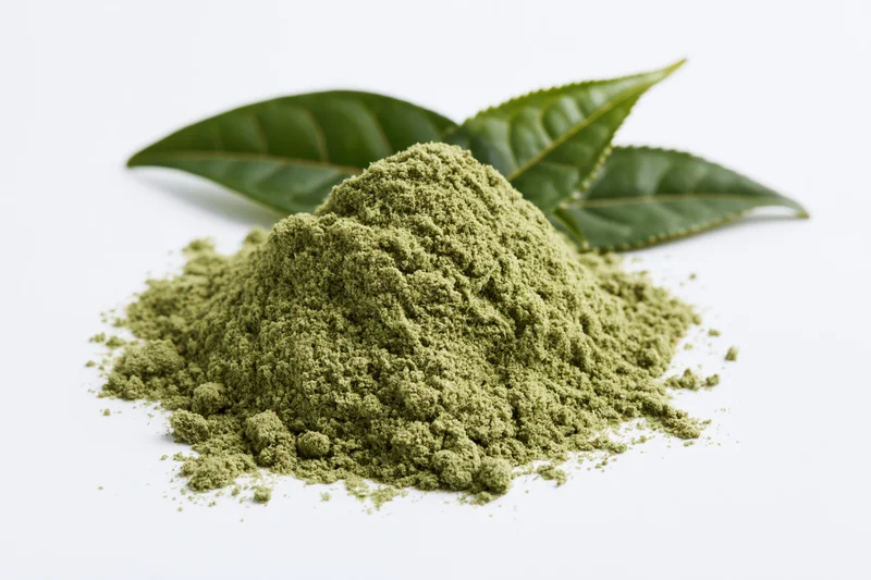 Mound of matcha green tea powder with fresh tea leaves on white background