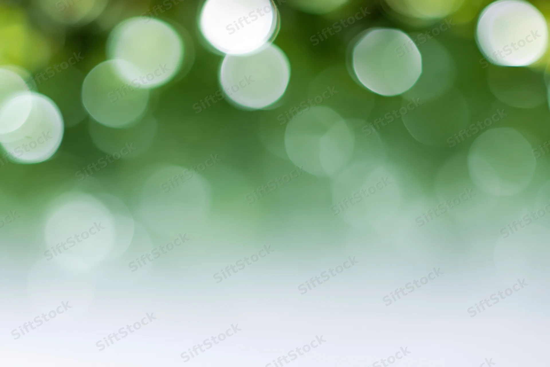 Soft out-of-focus bokeh background with large circular light spots in green and white, transitioning to white at bottom