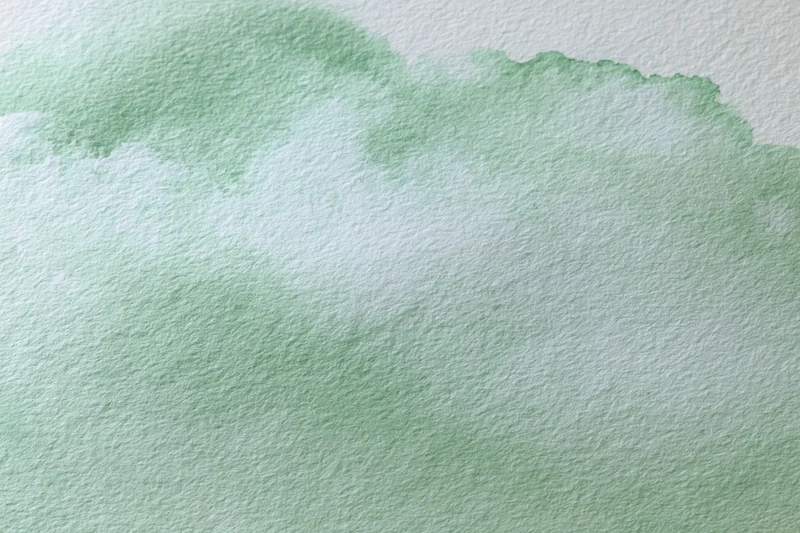 Soft green watercolor wash on textured paper abstract background
