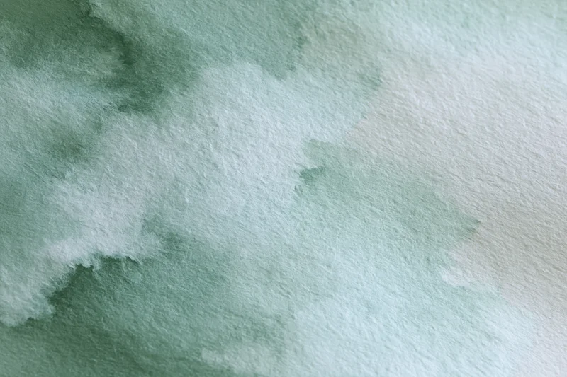 Soft watercolor wash in green and white on textured paper background