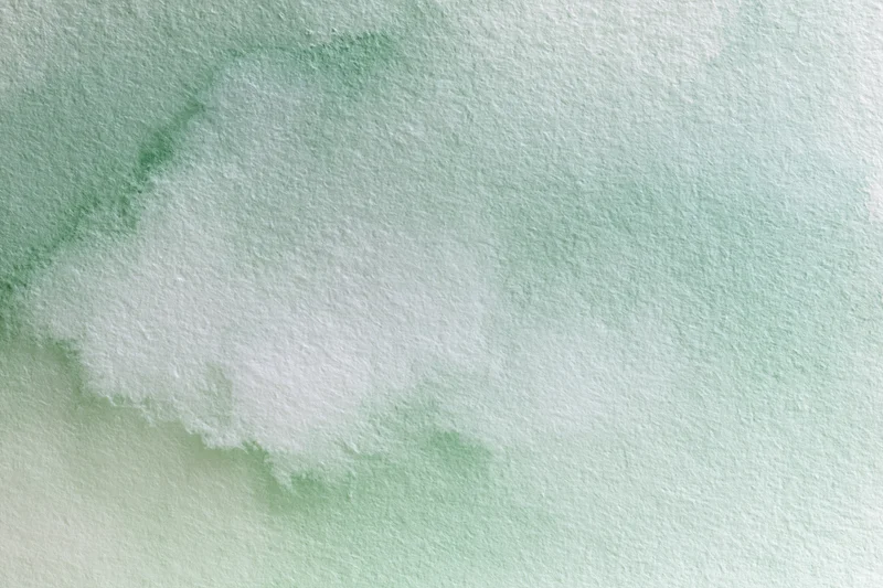 Soft green and white watercolor wash on textured paper abstract background