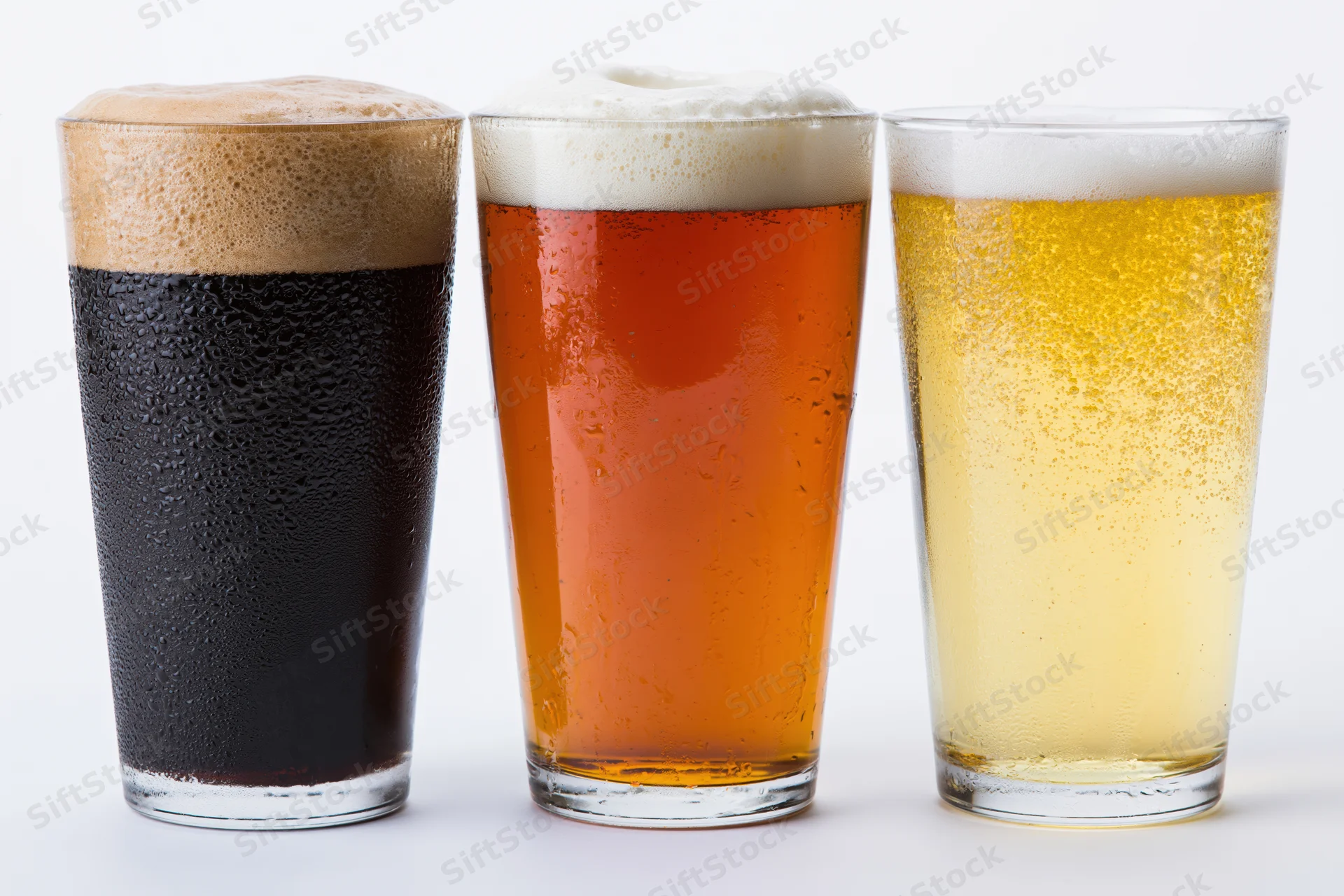 Three pint glasses of beer lined up side by side against a white background