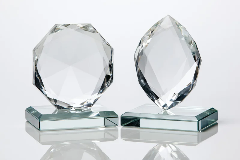 Two blank crystal glass trophies side by side on reflective bases