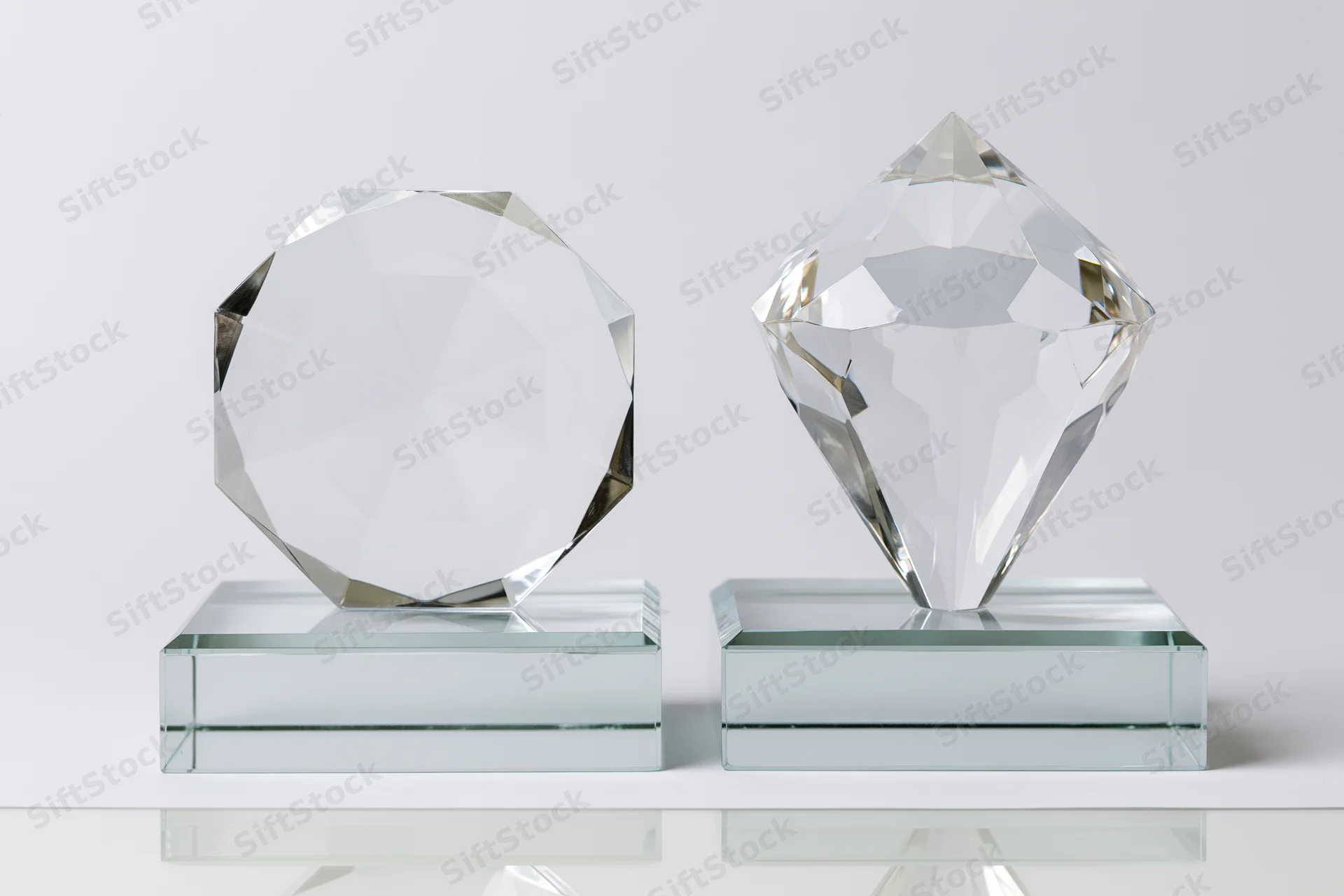 Two blank crystal glass trophies side by side on clear bases