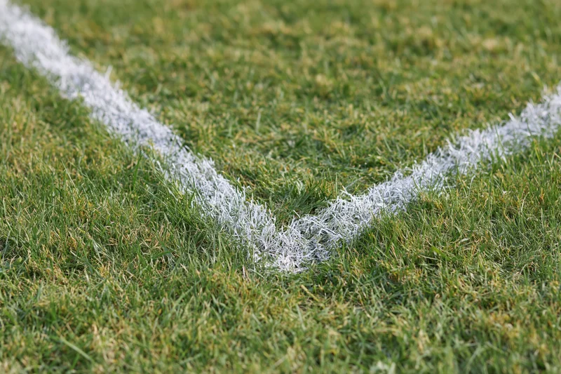 White painted boundary lines intersecting at a corner on a grass sports field