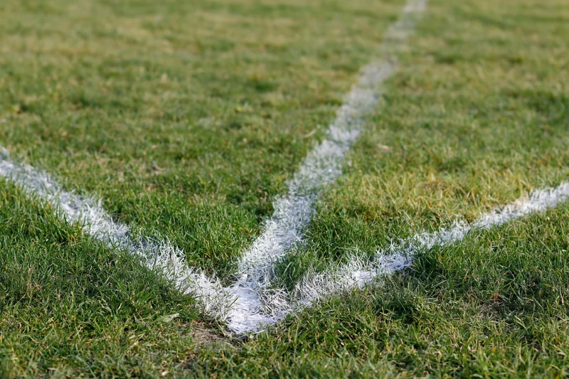 White painted boundary lines intersecting at a corner on a grass sports field