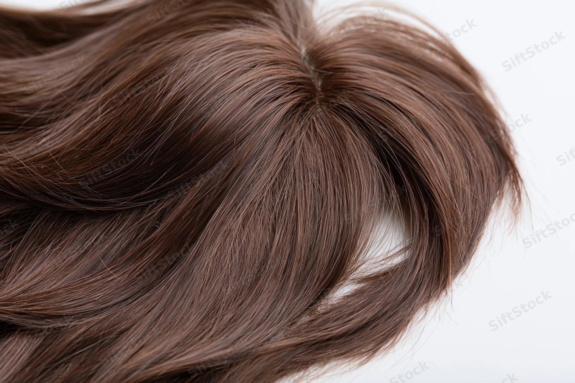 Dark brown wavy hairpiece lying flat on white background