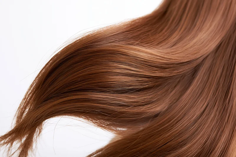 Flowing auburn-brown hair in motion against a white background