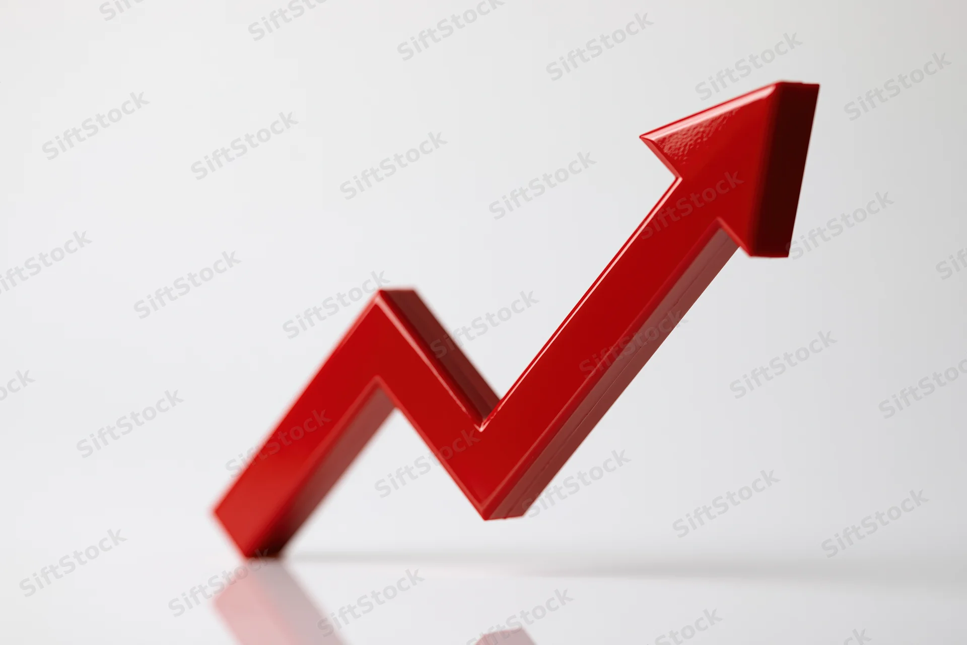Glossy red three-dimensional arrow zigzagging upward on white surface