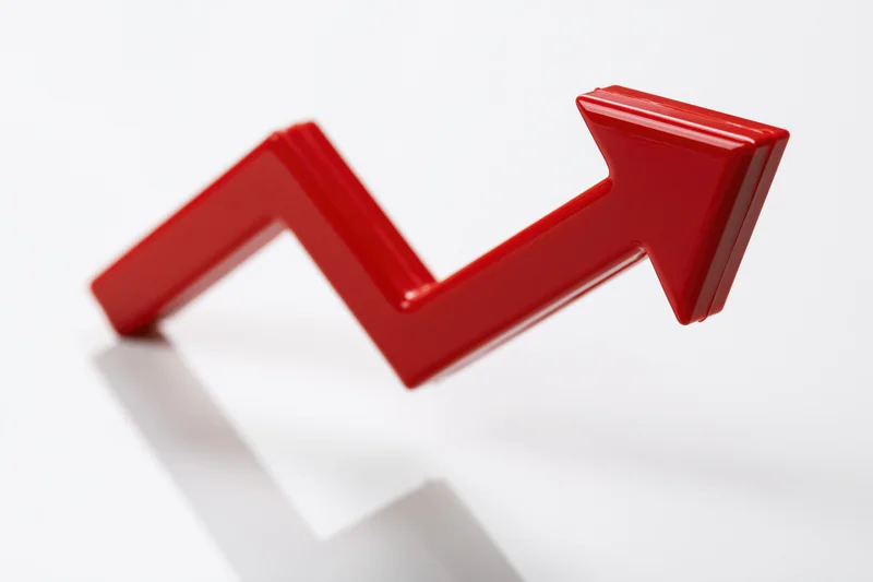 Glossy red three-dimensional arrow zigzagging upward on white background